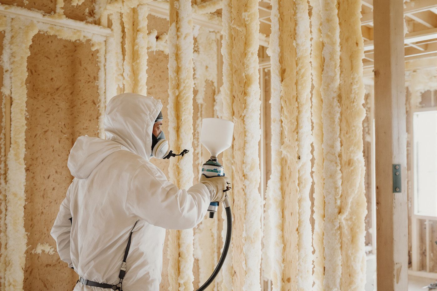Installer applying spray foam insulation across a Tulsa home attic rafters